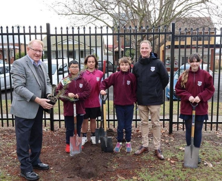 Students planting a tree with they mayor